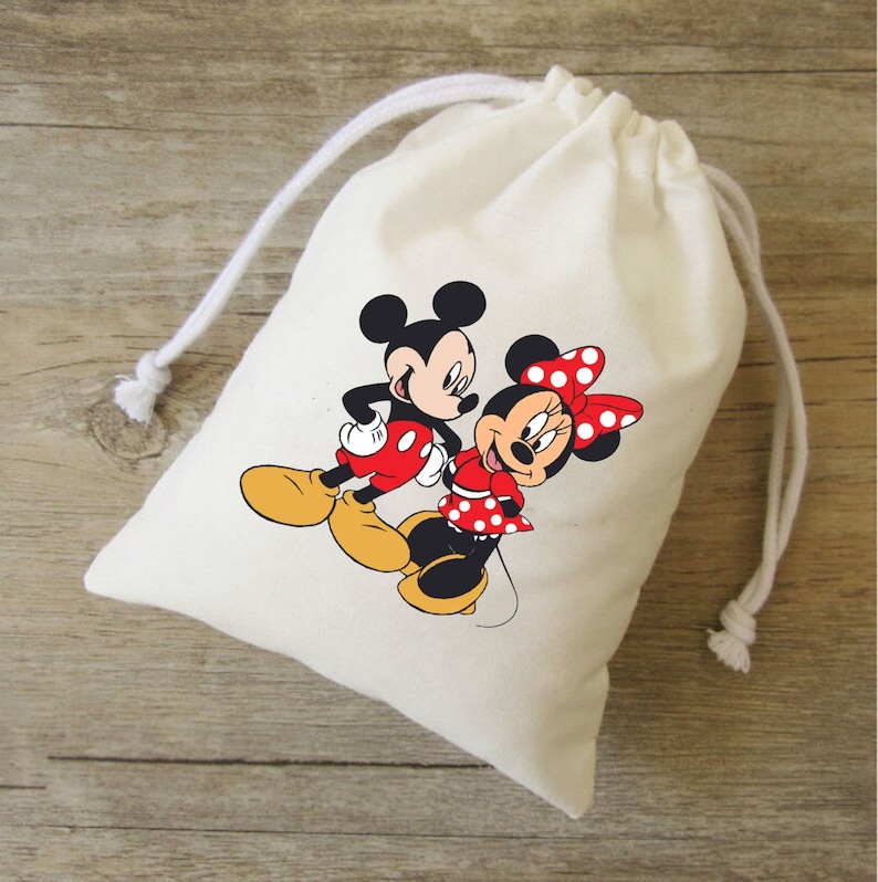 Może przedstawiać: Biała bawełniana torba ze sznurkiem do ściągania z nadrukowanym obrazkiem Myszki Miki i Minnie Mouse. Miki ma na sobie czerwone spodenki, a Minnie czerwoną sukienkę w białe kropki.