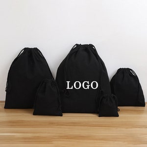 May include: Five black drawstring bags of various sizes. The largest bag has the word "LOGO" printed in white on the front.