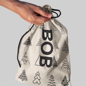 May include: A beige drawstring bag with black trees and the word "BOB" printed on it.