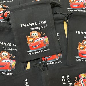 Puede incluir: Bolsas de cord&oacute;n negras con un tema de Cars. Las bolsas presentan a los personajes Rayo McQueen y Mate. El texto en las bolsas dice "&iexcl;Gracias por venir!" y "&iexcl;Gael 8&ordm; cumplea&ntilde;os!"