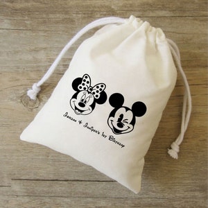 Może przedstawiać: Biały bawełniany worek ze sznurkiem, ozdobiony czarno-białymi obrazkami Myszki Miki i Minnie Mouse. Worek ma nadrukowany tekst "Jordan & Juniper's 1st Birthday".