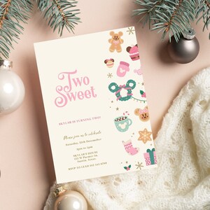 May include: A pink and white invitation card with the text "Two Sweet" in pink script. The card features a festive Christmas theme with illustrations of gingerbread cookies, a Mickey Mouse wreath, and other holiday icons. The text on the card reads "Skylar is turning two" and includes details for a birthday party.