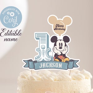 Può includere: Un topper per torta blu e bianco con Mickey Mouse che tiene un palloncino con la scritta "Happy Birthday". Il topper include anche uno striscione blu con il nome "JACKSON" e un grande numero "1" con decorazioni.
