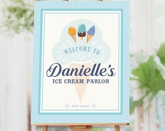 May include: A light blue sign on a wooden easel. The sign features the text "Welcome to Danielle's Ice Cream Parlor" with illustrations of ice cream cones and popsicles. The sign is framed with a dotted border and includes the year "EST 2020".