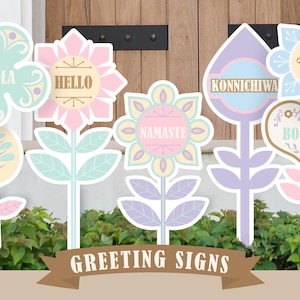 May include: A set of six colorful greeting signs shaped like flowers. Each sign features a different greeting in a different language, including "Hola", "Hello", "Namaste", "Konnichiwa", "Bonjour", and "Halla".