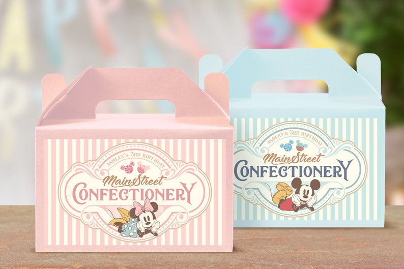 May include: Two pastel-colored favor boxes with a striped pattern and a vintage-style logo that says "Main Street Confectionery". The boxes feature Mickey and Minnie Mouse in a cartoon style. The pink box says "Ashley's 3rd Birthday" and the blue box says "Ashley's 3rd Birthday".