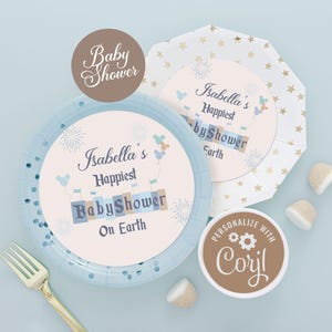 以下が含まれることがあります： 金色の星柄の青い紙皿と、「Isabella's Happiest Baby Shower on Earth」と書かれたパーソナライズされたステッカー。