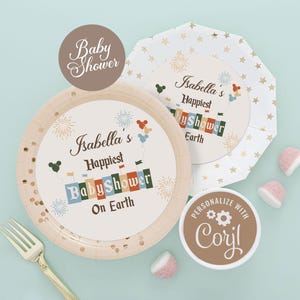 以下が含まれることがあります： 金色の星柄の紙皿のセットで、中央は白く、「Isabella's Happiest Baby Shower On Earth」の文字が書かれています。皿はカラフルな花火とミッキーマウスの風船で飾られています。 「Personalize with Coril」と書かれた茶色のステッカーも含まれています。