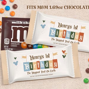 Könnte beinhalten: Eine weiße und braune M&M's-Süßigkeitenverpackung mit einer personalisierten Geburtstagsnachricht zum 1. Geburtstag von Henry. Die Verpackung ist in den Farben Blau, Grün, Orange und Rot gehalten und zeigt ein Mickey-Mouse-Ballon-Design. Der Text auf der Verpackung lautet "Henry's 1st Birthday" und "The Happiest Treat On Earth".