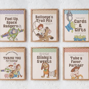 May include: Six framed prints with a retro design, showcasing characters and phrases from a well-known animated film. The prints feature phrases such as "Fuel Up, Space Rangers" and "Cards & Gifts," accompanied by character illustrations.