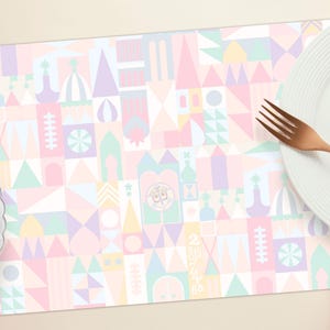 May include: A pastel pink, yellow, and blue patterned placemat with a geometric design. The placemat features a repeating pattern of squares, rectangles, and triangles.