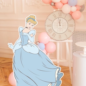 May include: A cutout of Cinderella in a light blue gown, with a clock showing midnight and a cluster of pink, white, and silver balloons. The background is a light pink wall with decorative molding, and a wooden floor.