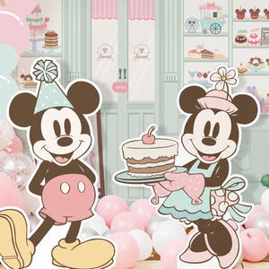 May include: A pink and white balloon arch with a Mickey Mouse and Minnie Mouse cutout. Mickey Mouse is wearing a blue and white hat and Minnie Mouse is wearing a pink and white dress and holding a cake. The background is a light blue and green wall with a candy shop theme.