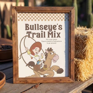 May include: A wooden framed sign featuring the text "Bullseye's Trail Mix" and an illustration of a cowgirl riding a horse. The sign has a brown frame and a checkered pattern at the top. The text "Fill your plate! There's plenty of adventure to go around!" is also included.