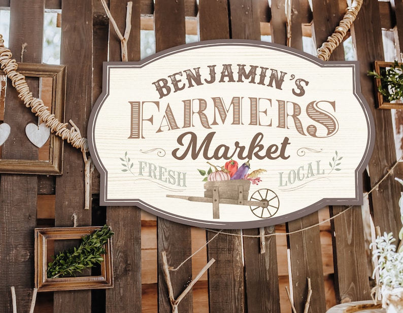 May include: A rustic wooden sign with the text "Benjamin's Farmers Market Fresh Local" in brown and white lettering. The sign is decorated with a wheelbarrow filled with vegetables and a floral design.