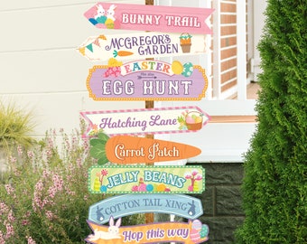 Puede incluir: Un conjunto de carteles coloridos con temática de Pascua con temas de conejito, zanahoria, búsqueda de huevos y gominolas. Los carteles están unidos a un poste de madera y tienen un estilo caprichoso y de dibujos animados.