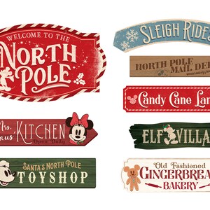 May include: Nine vintage-style wooden signs with a Christmas theme featuring Mickey Mouse and Minnie Mouse characters. The signs feature text such as "Welcome to the North Pole", "Sleigh Rides", "Candy Cane Lane", "Elf Village", "Mrs. Claus Kitchen", "Santa's North Pole Toy Shop", and "Old Fashioned Gingerbread Bakery".