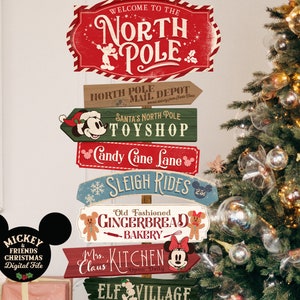 May include: A set of six wooden signs with a Christmas theme featuring Mickey Mouse and Minnie Mouse. The signs are decorated with red, green, and blue paint and have a vintage look. The signs are arranged in a stack and feature the text "Welcome to the North Pole", "North Pole Mail Depot", "Santa's North Pole Toyshop", "Candy Cane Lane", "Sleigh Rides", "Old Fashioned Gingerbread Bakery", "Mrs. Claus Kitchen", and "Elf Village".