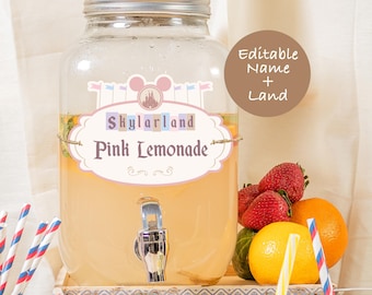 May include: A glass dispenser filled with pink lemonade, decorated with a label that says "Skylarland Pink Lemonade". The label features a cartoon castle and Mickey Mouse ears. The dispenser has a silver spigot and is sitting on a wooden surface.