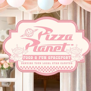 May include: A pink and cream-coloured Pizza Planet sign with the text "Pizza Planet" and "Food & Fun Spaceport". The sign features cartoon aliens and a planet graphic. The sign is hanging in front of a window with pink and white balloons.
