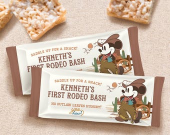 Op de afbeelding: Twee witte en bruine traktatiezakjes met een cartoonafbeelding van Mickey Mouse verkleed als cowboy. De zakjes hebben de tekst "Saddle up for a snack! Kenneth's First Rodeo Bash" en "No outlaw leaves hungry! Yee Haw!" erop gedrukt.