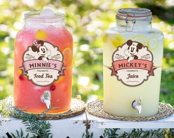 May include: Two glass beverage dispensers with spouts, one filled with pink iced tea and the other with yellow lemonade.  The dispensers have labels that say "Minnie's Favorite Iced Tea" and "Mickey's Favorite Juice".