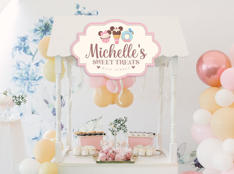 May include: A white dessert cart with a pink sign that says "Michelle's Sweet Treats Main Street" with a Mickey Mouse head and a cupcake, ice cream cone, and donut graphic. The cart is decorated with pink, white, and yellow balloons.