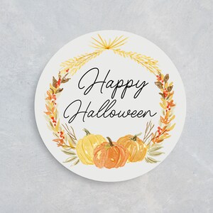 May include: A circular Halloween design featuring watercolour pumpkins and a wreath of autumnal leaves. The words "Happy Halloween" are written in black script. Ideal for seasonal decorations, this design is charming.