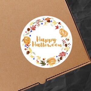 May include: A round sticker featuring a wreath of autumn leaves, pumpkins, and berries. The text "Happy Halloween" is in the centre of the sticker.