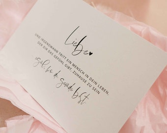 Könnte beinhalten: Eine weiße Karte mit schwarzem Text, der "Liebe" mit einem kleinen Herzsymbol lautet. Der Text setzt sich fort mit "UND IRGENDWANN TRITT EIN MENSCH IN DEIN LEBEN, DER DIR DAS GEFÜHL GIBT, ZUHAUSE ZU SEIN" und "gal, be de gerade bist".
