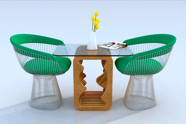 May include: A glass-top table with a unique wooden base, featuring a wavy design. Two green wire chairs with a white metal frame and a green cushion are placed on either side of the table. A vase with yellow flowers sits on the table, along with a magazine.