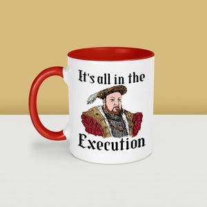 May include: White ceramic mug with a red interior and handle. The mug features a portrait of a historical figure and the text "It's all in the Execution" in black gothic font. The mug is a novelty item.