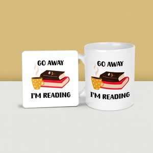 May include: A set of three ceramic mugs with a speckled, cream-coloured glaze. Each mug features a different hand-painted design: a blue and green leaf, a yellow flower, and a red berry. The mugs have a simple, rounded shape and a comfortable handle.