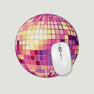May include: A white computer mouse sits on a round mouse mat. The mat displays a disco ball design with pink, purple, and yellow squares. The mouse has a scroll wheel and two buttons.