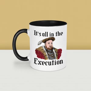 May include: White ceramic mug with a black interior and handle. The mug features a portrait of a historical figure with the text "It's all in the Execution". The design includes a detailed illustration of the figure in period clothing.