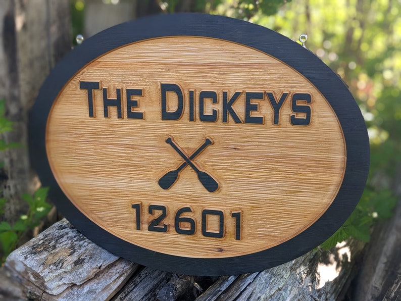 May include: Oval wooden sign with a black border. The sign says "THE DICKEYS" with a pair of crossed oars underneath and the number "12601" below the oars.