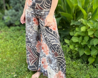 May include: A woman wearing a brown floral crop top and wide-legged pants with a black and white floral print. The pants have a high waist and a flowing silhouette.