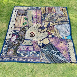 Puede incluir: Un tapiz de pared de patchwork con fondo azul y cuadrados de tela de colores. Los cuadrados de tela están decorados con bordados, lentejuelas y cuentas. El tapiz de pared tiene un borde con flecos.