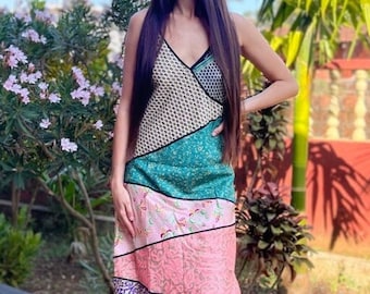 Könnte beinhalten: Eine Frau trägt ein mehrfarbiges Patchworkkleid mit V-Ausschnitt und einem grün-rosa-violetten Muster. Sie steht auf einer gefliesten Terrasse mit einem Palmenbaum im Hintergrund.