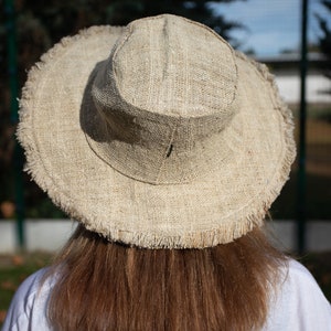May include: A wide-brimmed hat made of natural fibers with a frayed edge. The hat is a light brown color and is made of a woven material.
