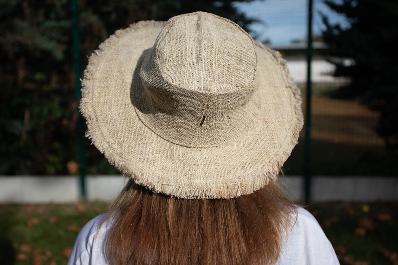 May include: A wide-brimmed hat made of natural fibers with a frayed edge. The hat is a light brown color and is made of a woven material.