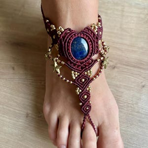 Può includere: Braccialetto per caviglia in macramè rosso borgogna con una pietra preziosa in lapislazzuli blu e accenti a forma di stella dorata.