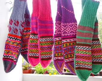 May include: Four pairs of colorful knitted socks with intricate patterns. The socks are in shades of gray, pink, purple, and green.