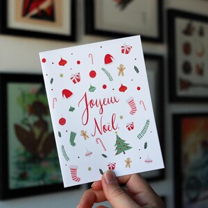 K&ouml;nnte beinhalten: Eine wei&szlig;e Karte mit einem roten und gr&uuml;nen Weihnachtsmotiv. Die Karte tr&auml;gt die Aufschrift "Joyeux No&euml;l" in roter Kursivschrift.