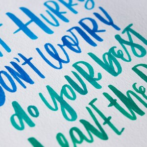 May include: Hand-lettered calligraphy in blue and green shades on white paper. The text reads "Don't hurry, don't worry, do your best, leave the rest."