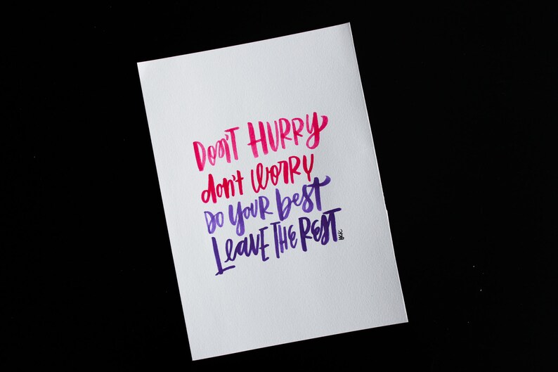 May include: A white card with a motivational quote written in pink and purple calligraphy. The quote reads "Don't hurry, don't worry, do your best, leave the rest."