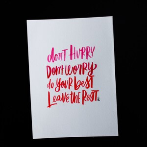 May include: A white card with pink and red handwritten text that reads "don't hurry don't worry do your best leave the rest".