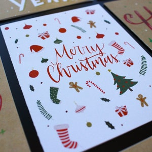 K&ouml;nnte beinhalten: Wei&szlig;e Karte mit roter Aufschrift "Merry Christmas". Die Karte ist mit roten und gr&uuml;nen Weihnachtsornamenten, Zuckerstangen und einem Weihnachtsbaum verziert.