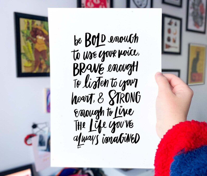 May include: Black and white inspirational quote handwritten on a white card. The quote reads: "be BOLD enough to use your voice, BRAVE enough To listen to your heart, & STRONG enough to live The Life you've always imagined"
