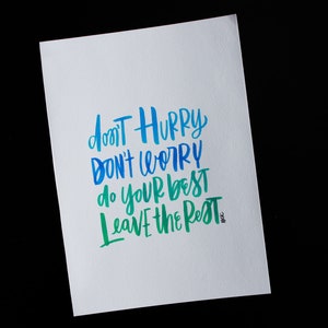 May include: A white card with blue and green lettering that reads "Don't hurry, don't worry, do your best, leave the rest".